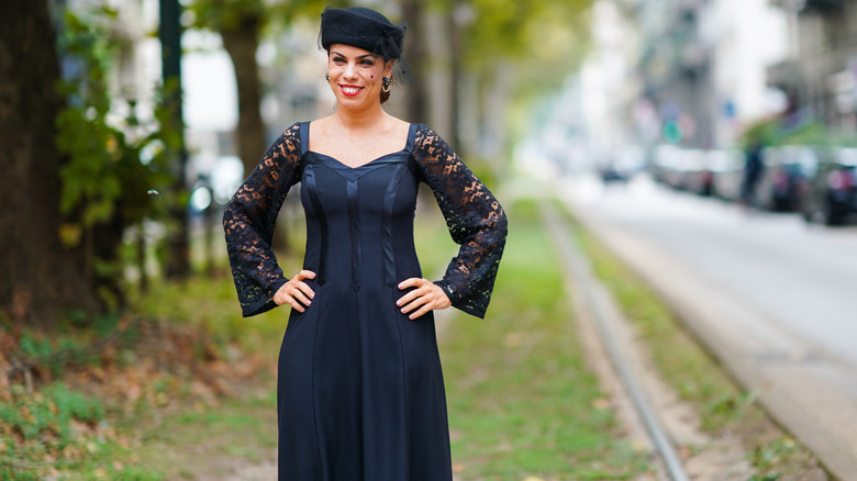 A woman wearing a lacey black dress with a hat and veil.