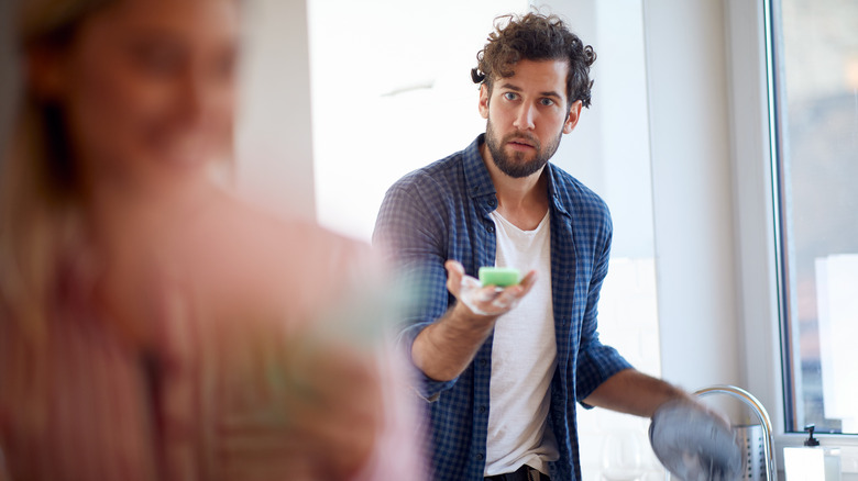Man showing his wife how to wash dishes 