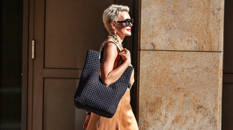 A stylish older woman wearing a textured bag in the summer and accessories