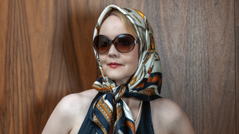 a stylish older woman accessorizing with a silk scarf