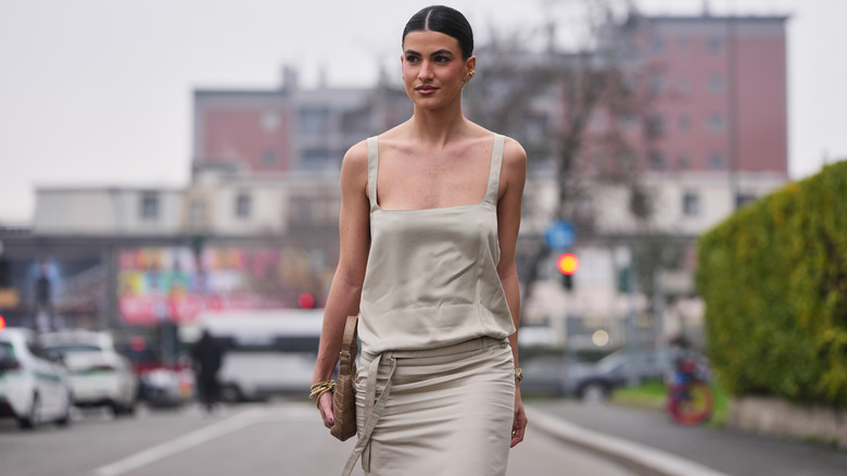 A woman wearing a boring beige dress leaning minimalist