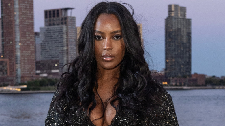 Ciara Miller posing with curly hair in front of the Hudson River