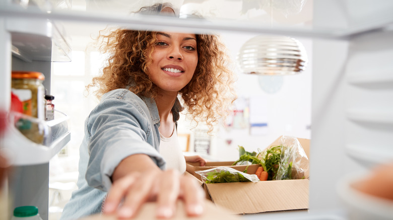 Woman stocking fridge