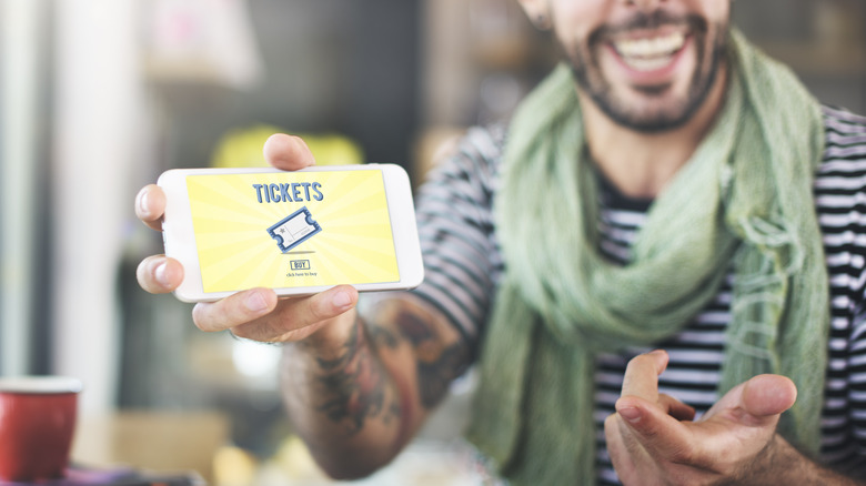 Smiling man with event tickets on phone