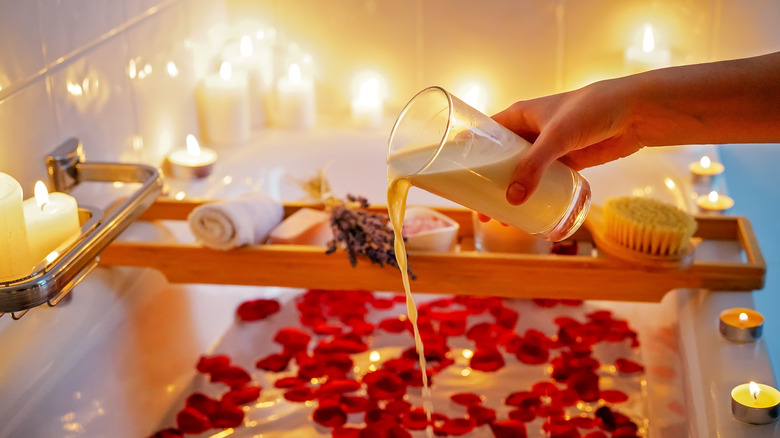 Woman's hand pouring milk into bath