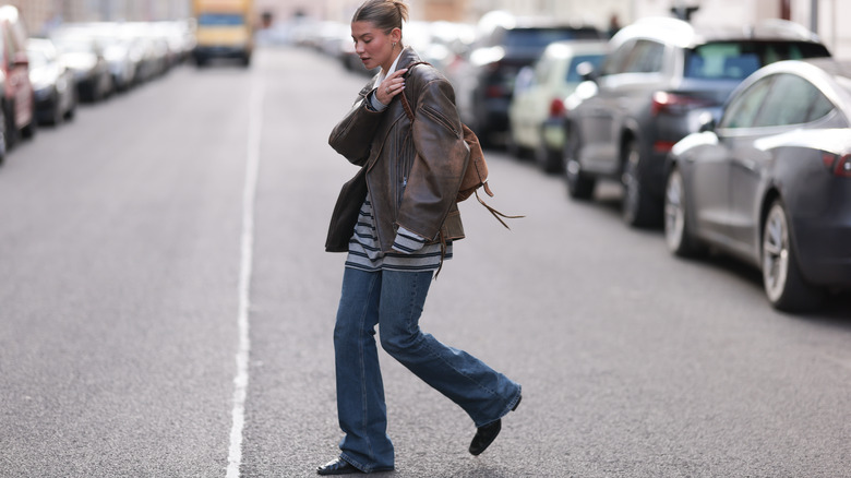 A woman wearing bootcut jeans paired with a leather jacket and striped top