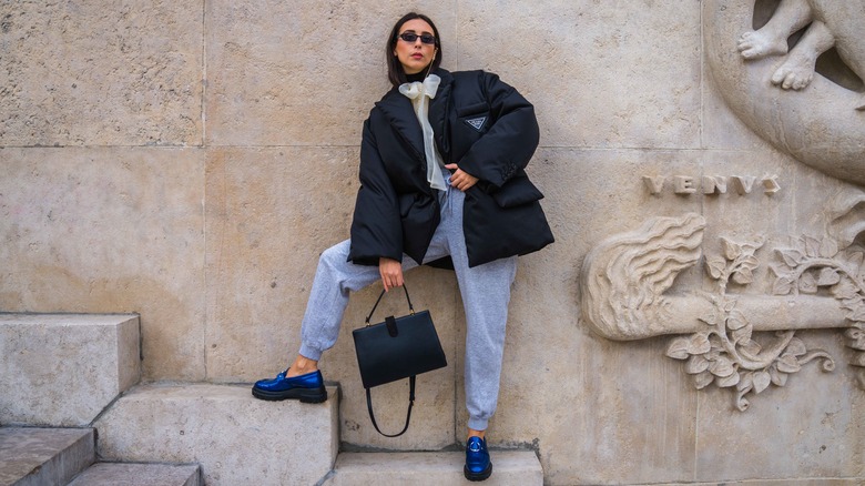 Woman wearing bright blue loafers and athleisure while posing on a staircase.