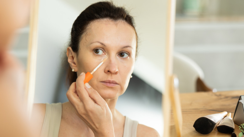 Model applying concealer with its applicator