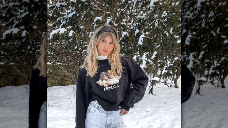 Girl wearing a white turtleneck under a Fiorucci sweatshirt.