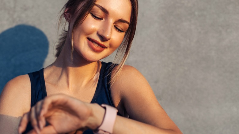 female resting after a workout looking at her watch