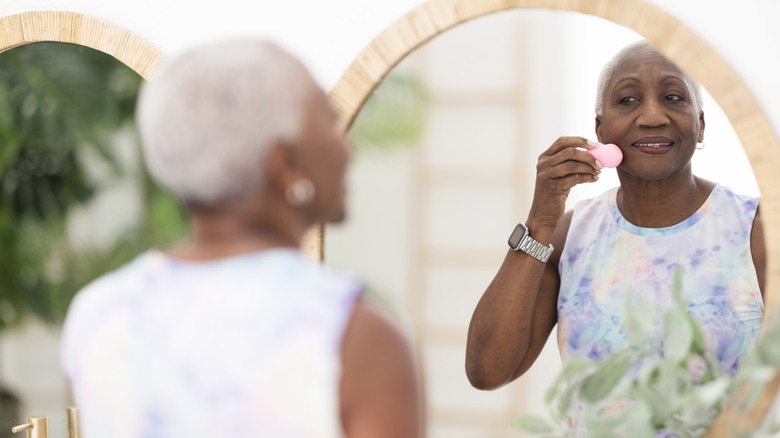 woman using beauty sponge looking in mirror