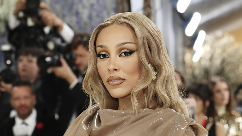 Doja Cat posing at the 2026 Met Gala wearing a beige top and her hair down.