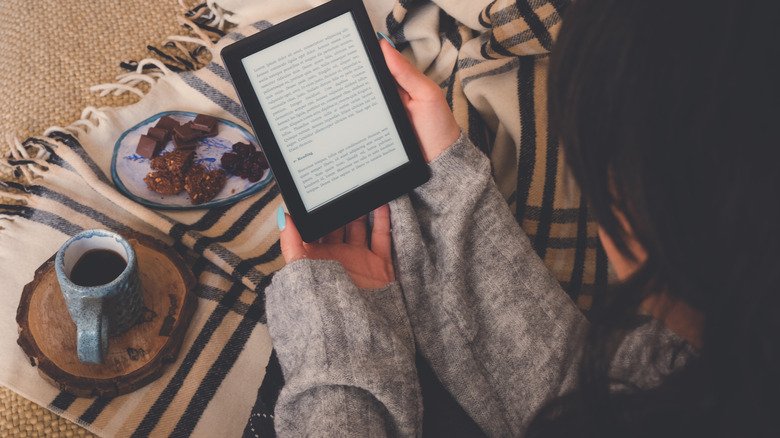 Woman reading on kindle drinking coffee