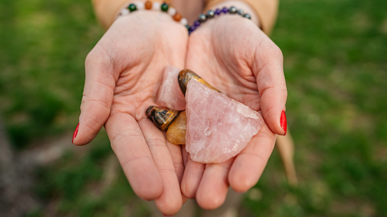 Hands holding rose quartz, tiger's eye 