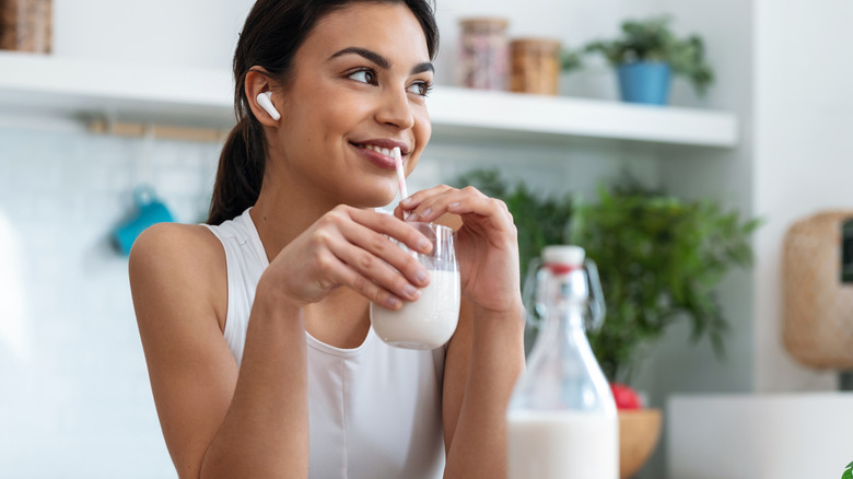 A woman drinking milk through a straw.