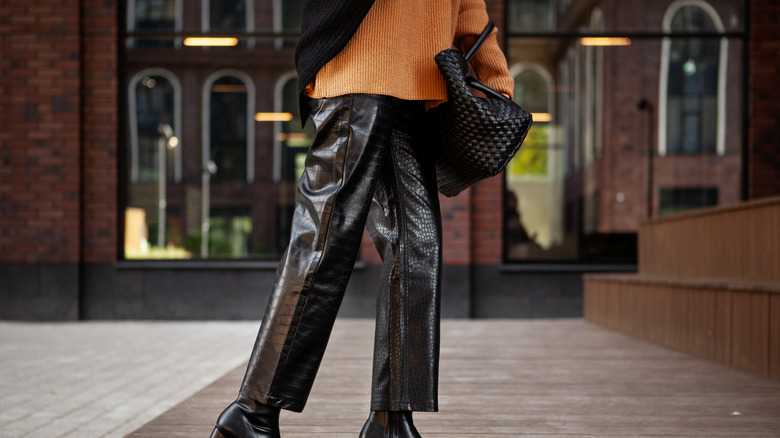 A model wearing faux leather pants with an orange top