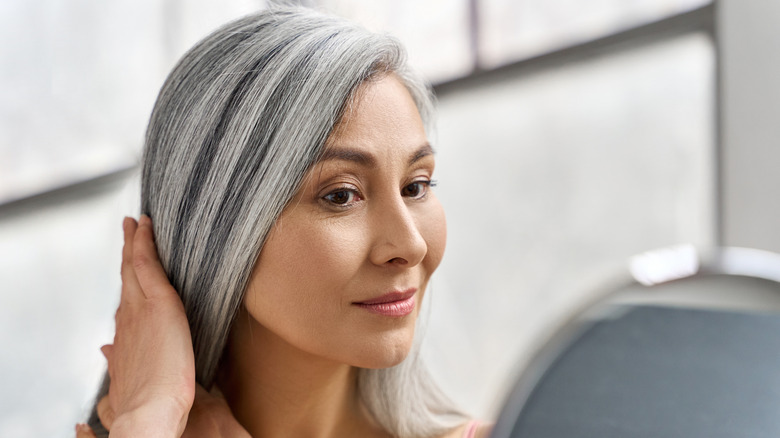 Woman with gray hair looking in the mirror