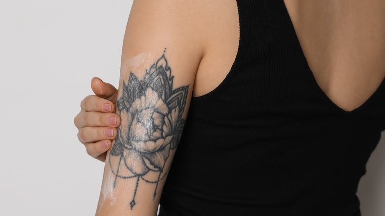 woman apply cream to tattoo