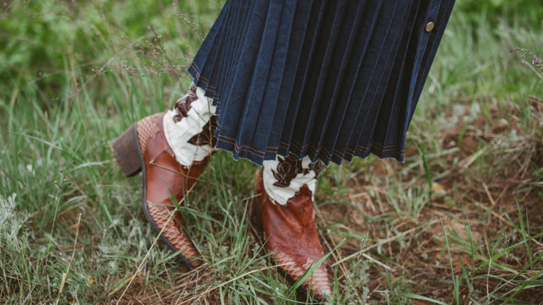 Woman wearing a denim skirt with cowboy boots
