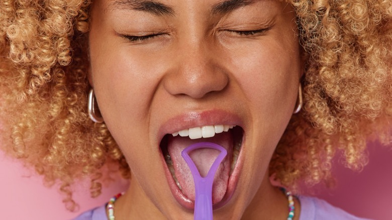 Woman using a tongue scraper