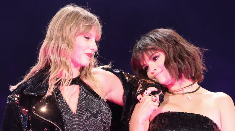 Taylor Swift and Selena Gomez cuddle and hold hands while performing together.