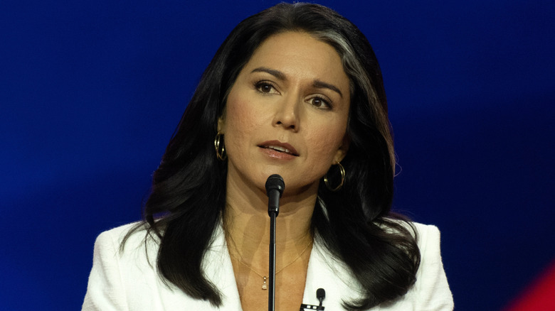 Tulsi Gabbard in a white suit photographed while speaking at the CPAC