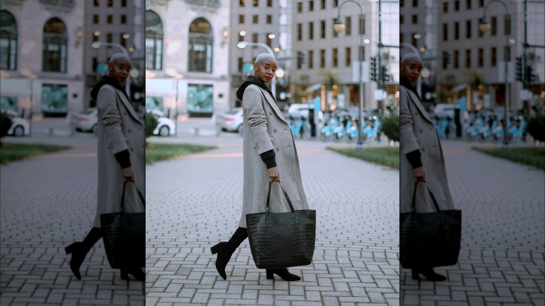 Woman carrying a croc-embossed black tote bag.