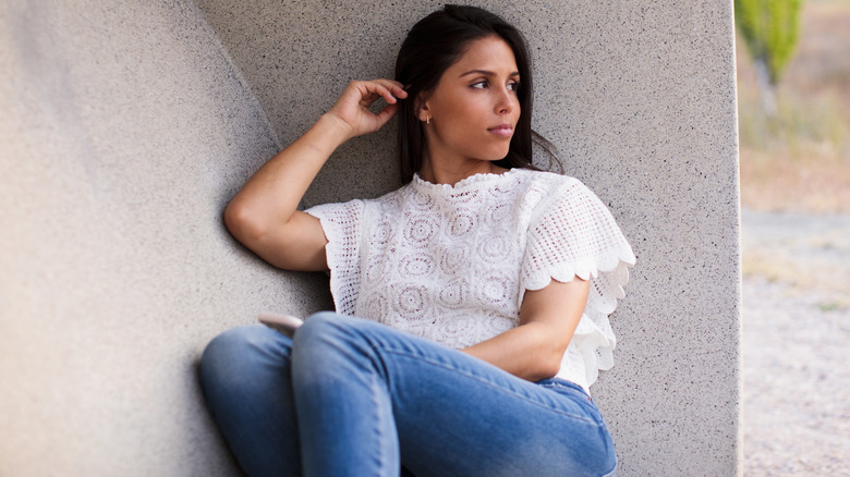 A woman wearing a white embroidered shirt with jeans.