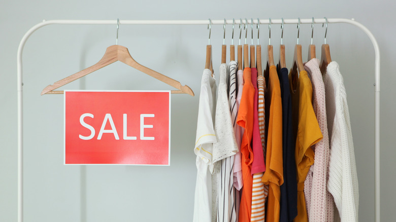 Rack of discounted clothing with sale sign