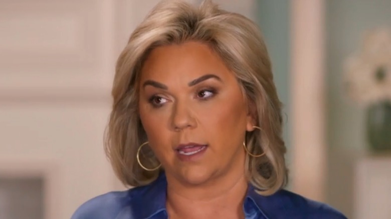 Julie Chrisley wearing a blue shirt and hoop earrigs