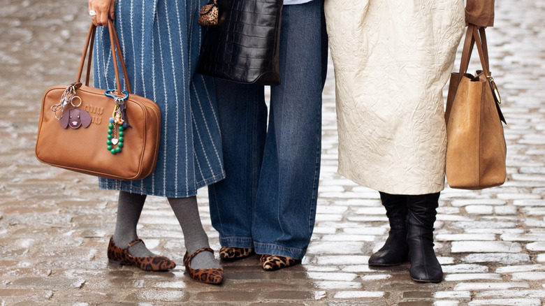 A person standing with baggy jeans and suede ballet flats