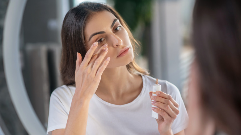 Woman applying concealer under her eye