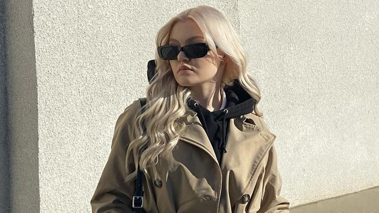 Woman wearing a trench coat over a sweatsuit.