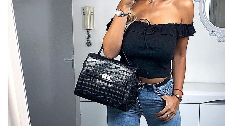woman holding crocodile print handbag