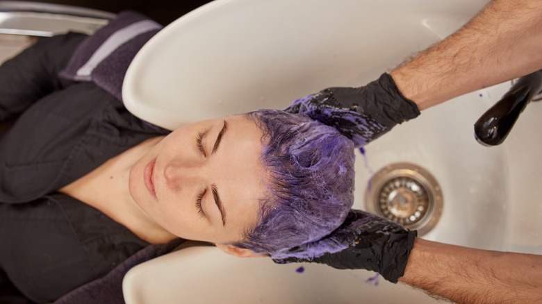 woman applying purple toner to hair
