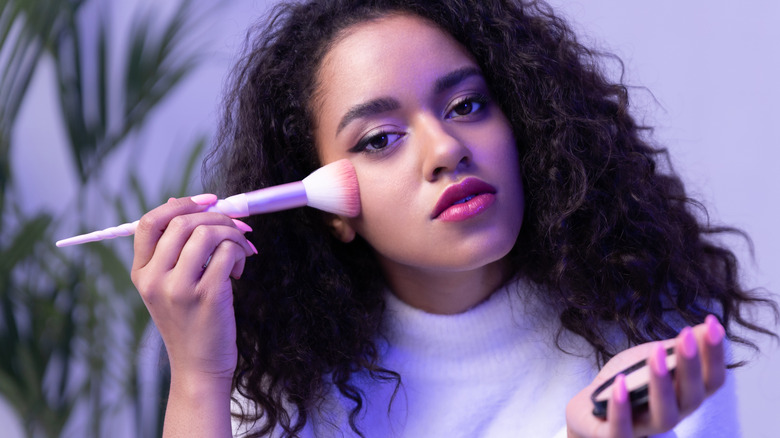 woman applying makeup to face 