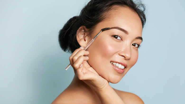 woman holding spoolie to eyebrow