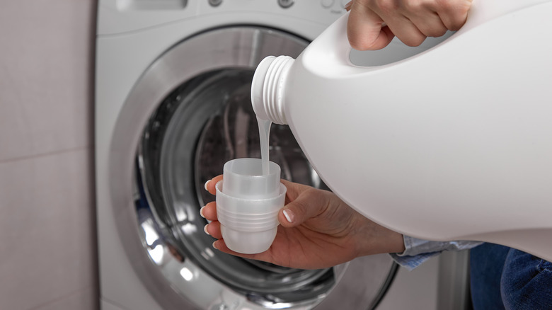 Person pouring laundry detergent