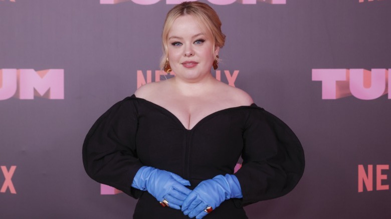 Nicola Coughlan posing in a black dress with blue gloves