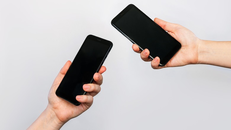 Two hands hold two phones