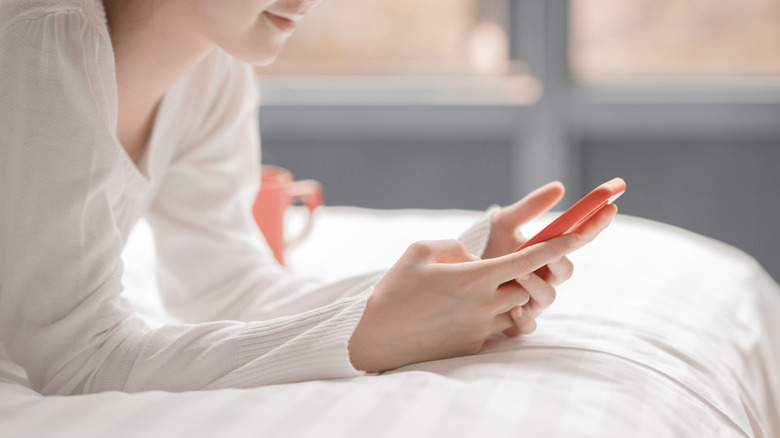 Woman uses phone in bed