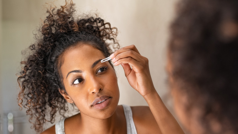 woman plucking her eyebrows