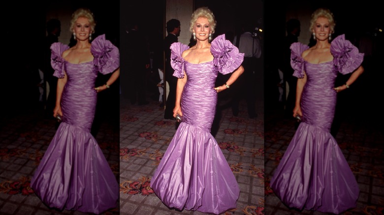Eva Gabor smiles wearing a voluminous lilac gown with puff sleeves.