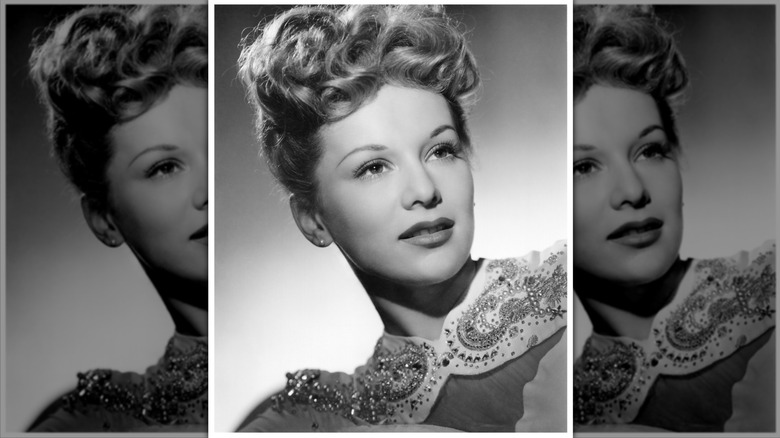 Eva Gabor poses wearing an embellished collar and a poodle-top updo