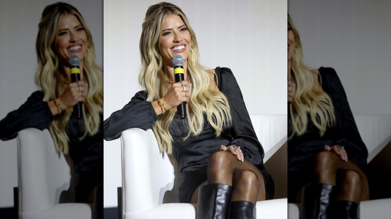 Christina Haack speaks into a microphone with long blond hair extensions worn seamlessly.