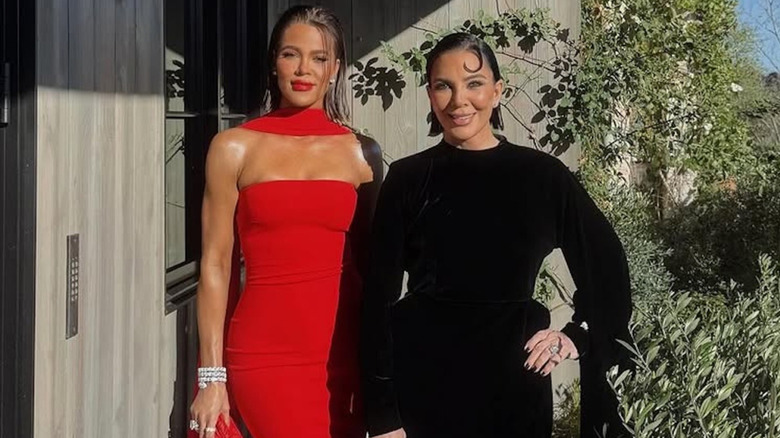 Khloé Kardashian in a dramatic red gown posing next to Kris Jenner in a black glown with slick hair
