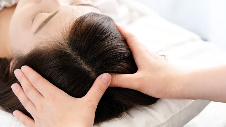 Person massaging woman's head