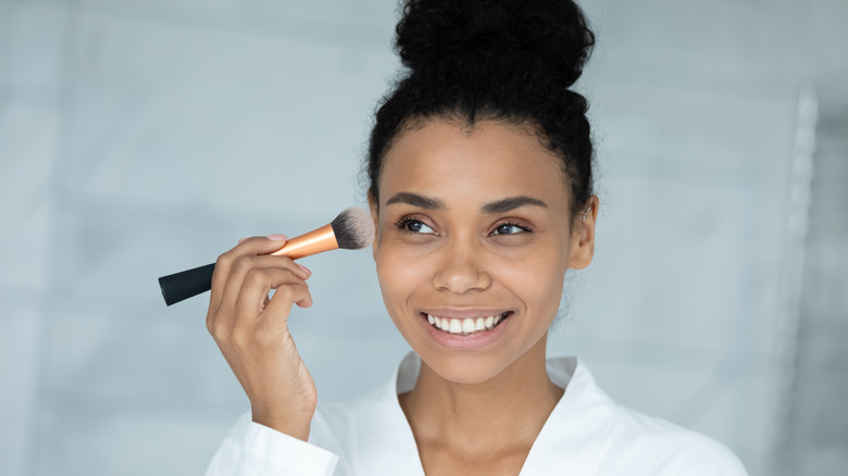 Woman applying bronzer to temple