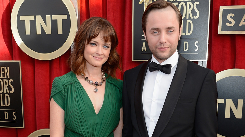 Alexis Bledel walking a red carpet in a green dress with her ex-husband, Vincent Kartheiser