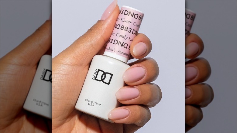 manicured hand holding nail polish bottle